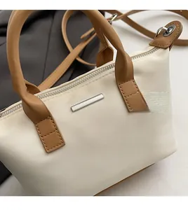 Detail of minimalist cream bucket bag showing textured fabric and brown leather trim