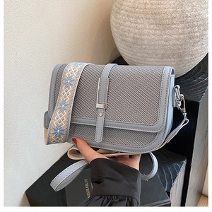 Detail of light blue crossbody bag with woven texture and geometric patterned wide strap