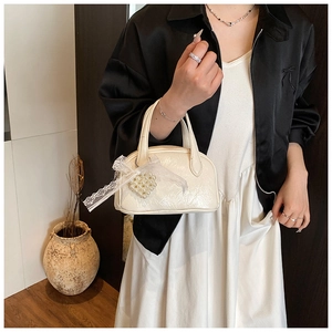 Détail du sac oreiller crème avec nœud en dentelle et pendentif cœur en perles