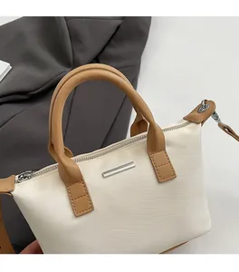 Detail of minimalist bucket bag showing reinforced brown handle and metal zipper closure
