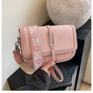 Detail of pink crossbody bag with woven fabric texture and wide patterned strap