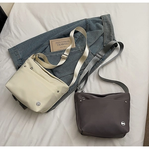 Vue détaillée des sacs seaux en nylon beige et gris avec bandoulières réglables