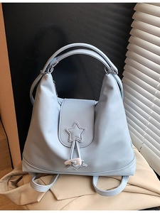 Light blue faux leather backpack with star stitching and horn buckle in a lifestyle setting