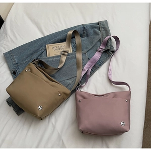 Détail de sacs seaux en nylon kaki et rose avec des bandoulières réglables