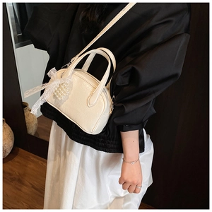 Détail du sac à main blanc plissé avec nœud en dentelle et pendentif en perles