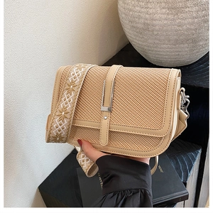 Detail of beige woven crossbody bag with geometric pattern wide strap and metal clasp