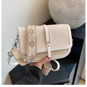 Detail of retro straw crossbody bag with white leather trim and geometric embroidery strap