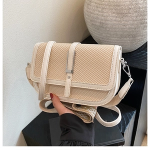 Detail of handwoven straw handbag featuring beige leather trim and silver metal buckle