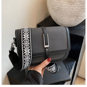 Detail of grey woven small square bag with leather trim and wide geometric strap