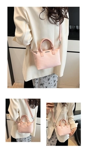 Detail of light pink bucket bag with silver logo plaque and adjustable leather shoulder strap