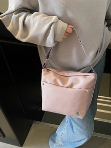 Sac seau en nylon délavé rose pâle avec bandoulière réglable porté par un mannequin