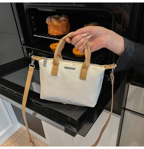 Close-up of beige water-resistant nylon bucket bag with brown leather handles and silver hardware