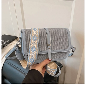 Detail of grey-blue woven handbag featuring a vintage metal clasp and ethnic canvas strap