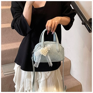 Détail du sac à main vert menthe plissé avec noeud en dentelle et breloque perle