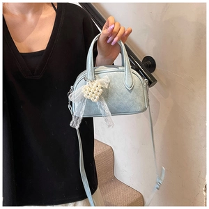 Détail du sac à main bleu clair en simili cuir avec pendentif cœur en dentelle et perles