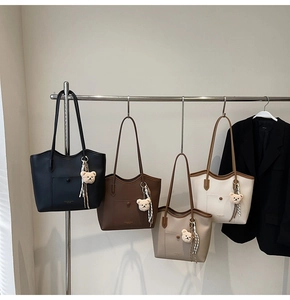 Detailed display of four tote bags in diverse colors with plush bear charms and scarves