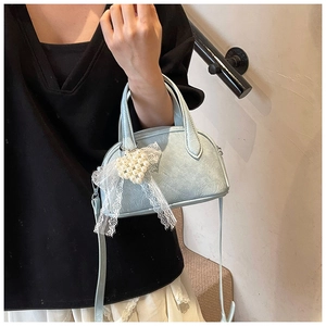 Détail du sac à main en similicuir bleu clair avec nœud en dentelle et pendentif perle