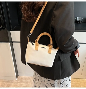 Detail of canvas bucket bag with brown leather straps worn over a black blazer