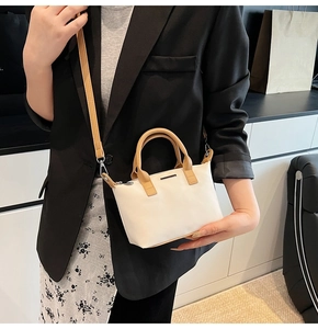 Detail of cream bucket bag with caramel leather straps and silver metal hardware accents