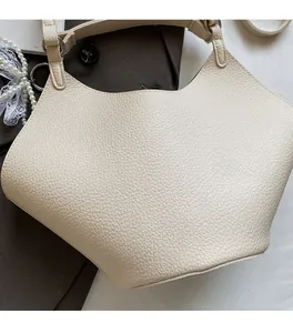 Detailed macro view of the cream pebble grain texture and metallic hardware on the bag