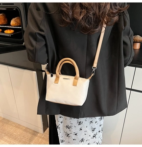 Detail of minimalist bucket bag with leather handles shown in a modern kitchen setting