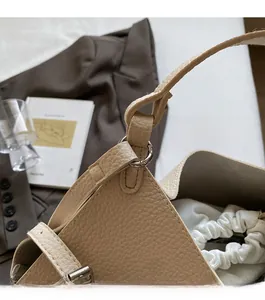 Detail of apricot lychee texture leather bag with metal rings and white drawstring pouch