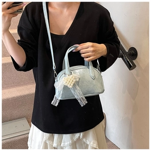 Sac bowling bleu clair avec charms en dentelle porté par un mannequin au style épuré