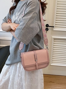 Pink crossbody bag with woven texture and embroidered wide strap on female model