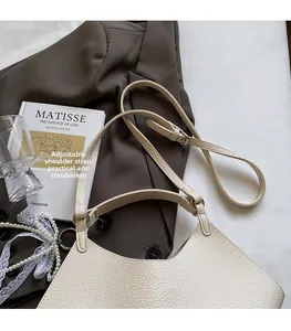 Detail showing the adjustable thin leather strap and metal buckle of the cream bucket bag