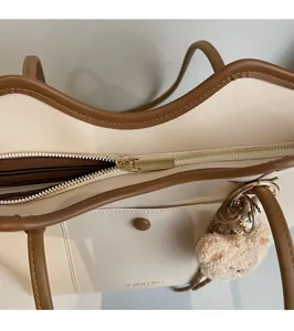 Detailed close-up of smooth gold zipper hardware and interior pocket of the tote bag