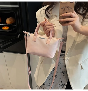 Detail of pink faux leather bucket bag with metal trim and adjustable strap