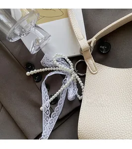 Detail of cream white lychee leather bag with elegant pearl and lace bow charms