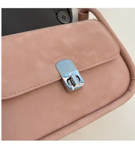 Detail of pink matte leather crossbody bag with silver striped textured metal twist lock