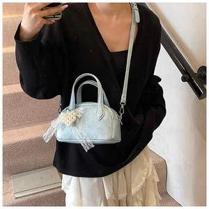 Détail du sac à main plissé bleu clair avec breloque cœur en perles et nœud en dentelle