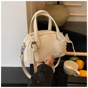 Détail du sac oreiller crème avec texture froissée et breloque en dentelle de perles