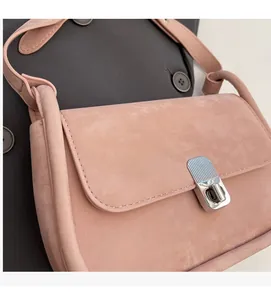 Detail of light pink shoulder bag featuring soft suede texture and silver twist lock