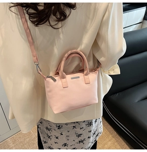 Detailed side view of a small pale pink bucket bag styled with a white blazer and floral dress