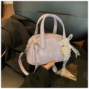 Détail du sac à main en cuir verni lilas plissé avec nœud en dentelle et perles