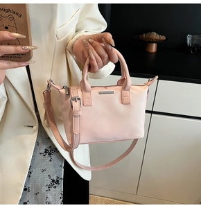 Detail of light pink tote bag with silver metal bar and dual top handles for daily use