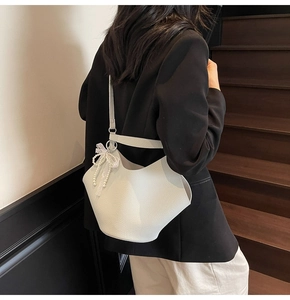 Litchi pattern bucket bag with pearl lace bow detail worn by a model on stairs
