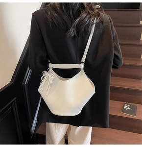 Dettaglio di una borsa a secchiello in pelle martellata bianca con fiocco di perle