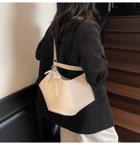 Litchi texture leather tote bag with pearl and lace bow charm detail on stairs