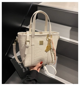 Detail of cream leather bucket bag with cute embossed cartoon bears and silk scarf
