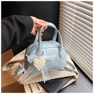 Détail du sac Boston bleu clair avec breloque cœur perle et nœud en dentelle