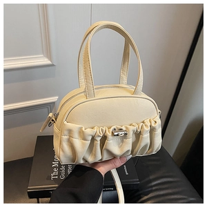 Détail du sac à main plissé blanc cassé avec fermoir rotatif argenté et texture chic