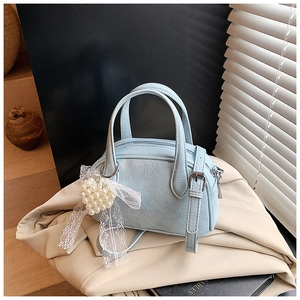 Détail du sac boston bleu clair avec texture vintage et breloque en dentelle