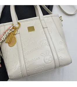 Detailed view of cream leather bucket bag with cute cartoon bear embossing and gold charms