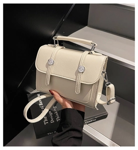 Détail du sac à main beige en similicuir avec boucle argentée ronde et poignée solide