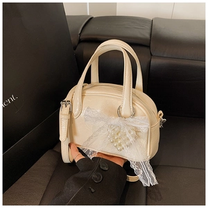Détail du sac polochon blanc crème avec nœuds en dentelle et décorations en perles