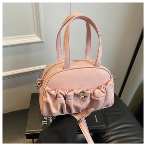 Détail latéral du sac bowling rose plissé en cuir avec fermoir rotatif argenté et anse